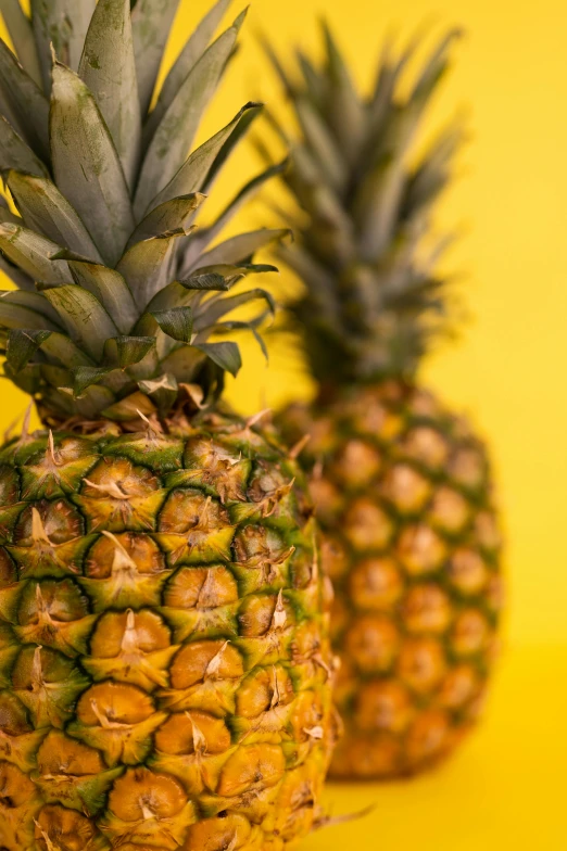 two pineapples on a yellow background, by Matt Stewart, pexels, 2 5 6 x 2 5 6 pixels, taken with sony alpha 9, upclose, recipe
