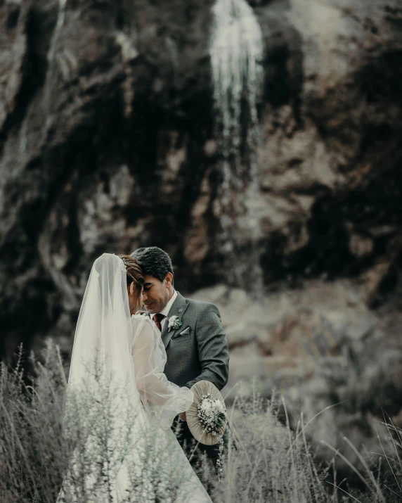 a bride and groom standing in front of a waterfall, unsplash contest winner, thumbnail, rustic, grey, attractive photo