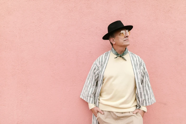 a man standing in front of a pink wall, inspired by Wes Anderson, unsplash, bauhaus, wearing cylinder hat, wearing a cardigan, 15081959 21121991 01012000 4k, middle - age