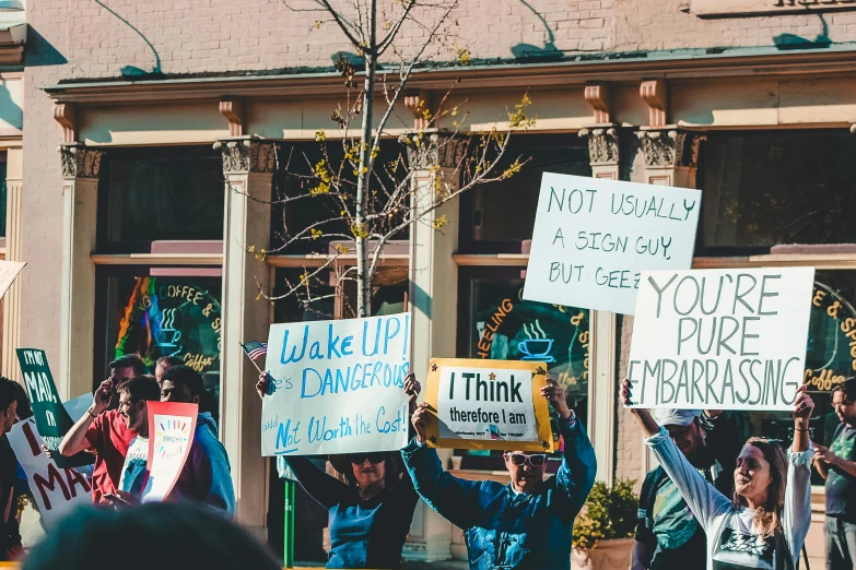 a group of people holding signs in front of a building, by Julia Pishtar, trending on pexels, waking up, endangered, from wheaton illinois, thumbnail