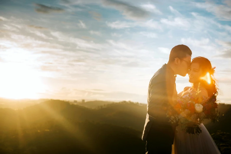 a bride and groom kissing in front of the sun, pexels contest winner, stunning vista, brightly lit, golden hour 4k, bottom angle