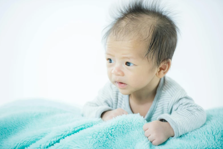 a baby laying on top of a blue blanket, unsplash, mingei, thinning hair, looking to his left, asian male, scientific photo