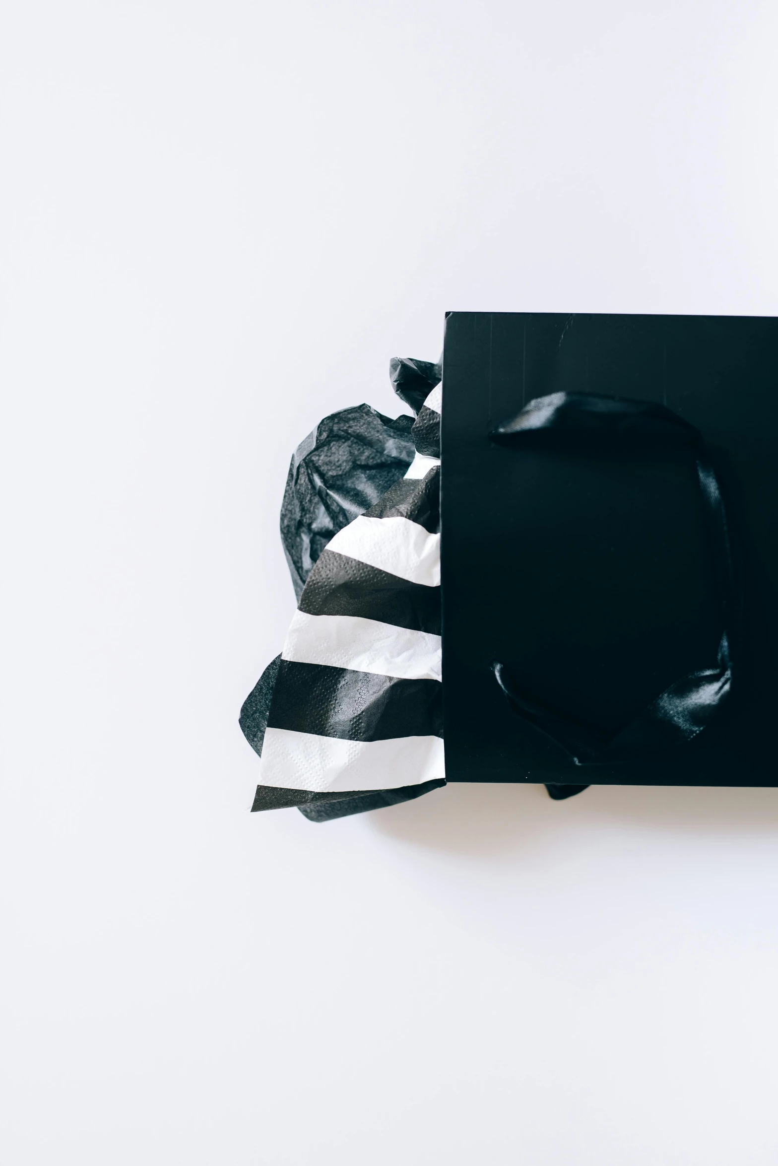 a black gift bag sitting on top of a white table, pexels contest winner, stripes, packaging design, profile picture, high-contrast