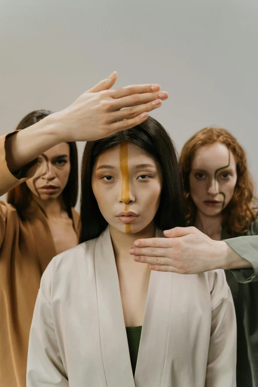 a group of women standing next to each other, inspired by Vanessa Beecroft, trending on pexels, renaissance, hands shielding face, asian face, ochre, deity)