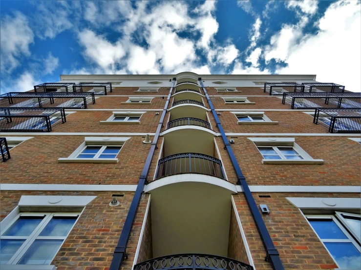 a tall brick building with many windows and balconies, by Carey Morris, unsplash, show from below, blue skies, ten flats, high quality picture