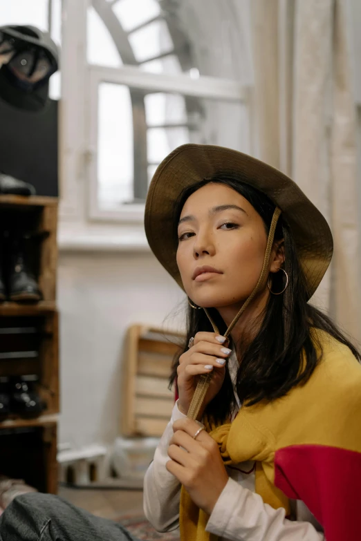 a woman sitting on the floor wearing a hat, inspired by Kim Tschang Yeul, trending on pexels, in a workshop, portrait of tall, inuk, yellow