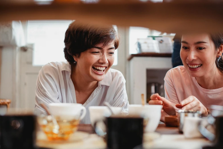 two women sitting at a table with cups of coffee, pexels contest winner, happening, head bent back in laughter, japanese collection product, family dinner, aussie baristas