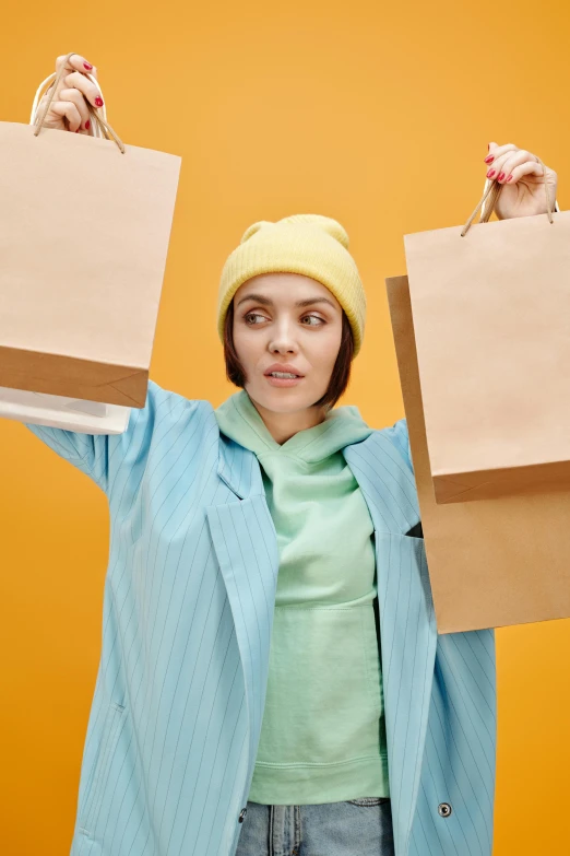 a woman holding two shopping bags over her head, a colorized photo, pexels, yellow clothes, annoyed, thumbnail, brown paper