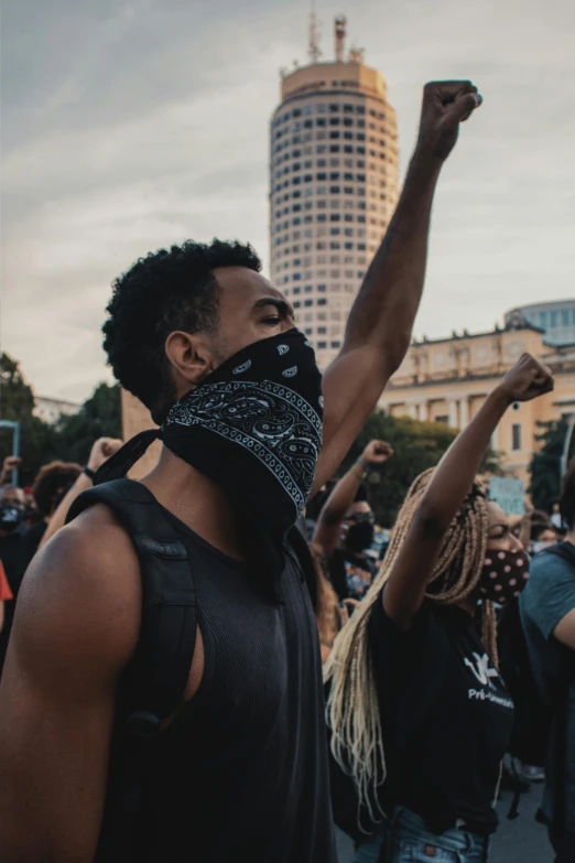 a man with a bandana standing in front of a crowd, trending on unsplash, black arts movement, riot shields, wearing a tanktop, man wearing a closed cowl, profile image