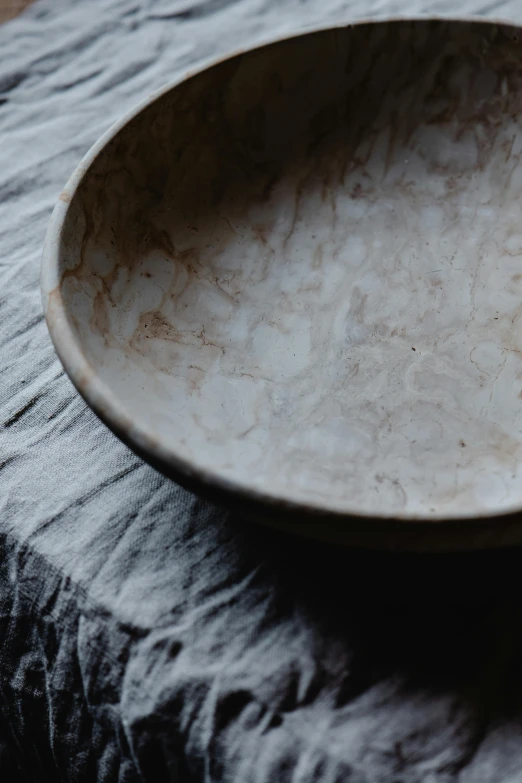 a close up of a plate on a table, a marble sculpture, inspired by Josefina Tanganelli Plana, unsplash, bowl, dark natural glow, linen, waxed