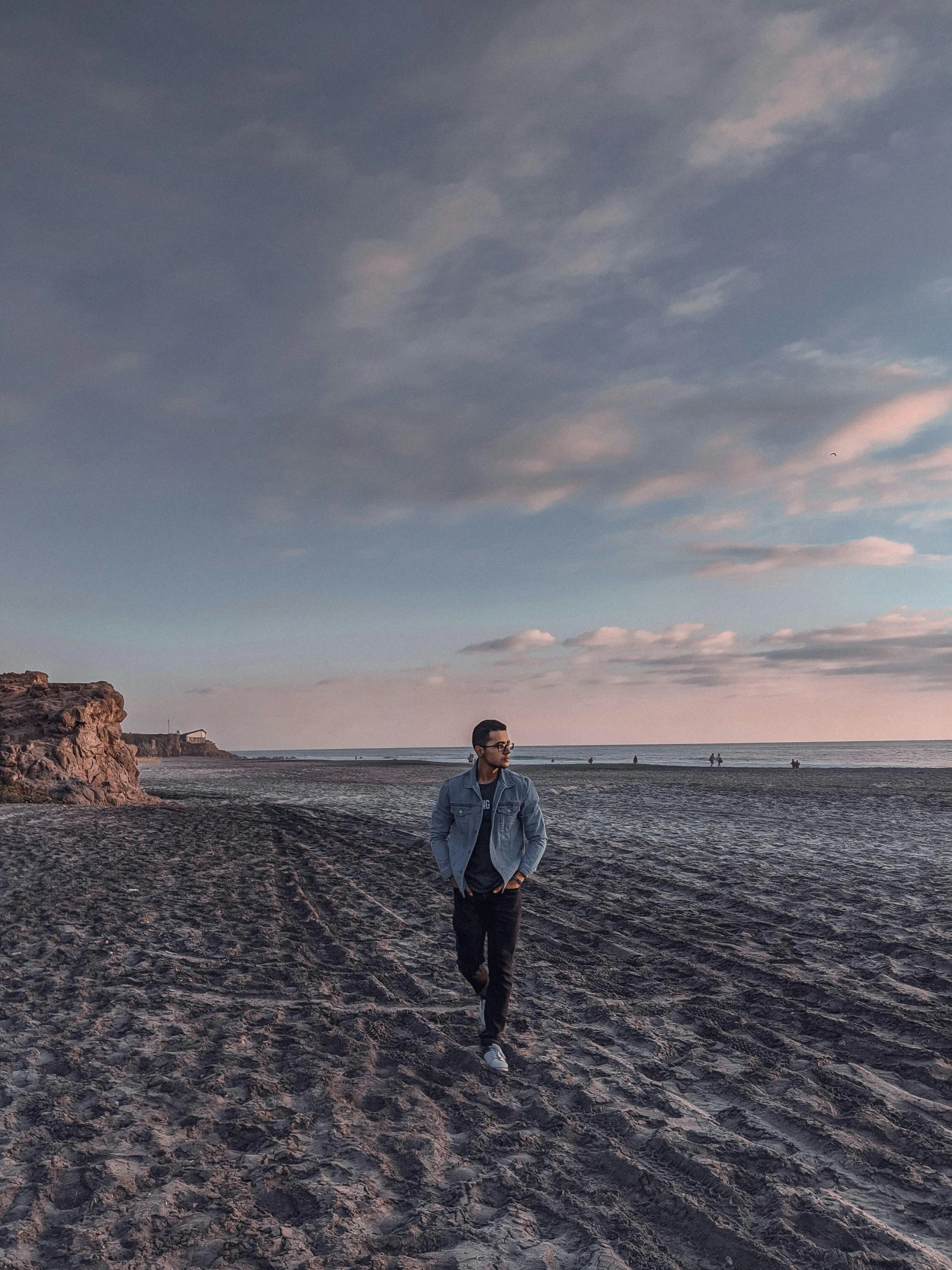 a man standing on top of a sandy beach, an album cover, pexels contest winner, 8k hdr dusk light, walking to the right, liam, posing for a picture