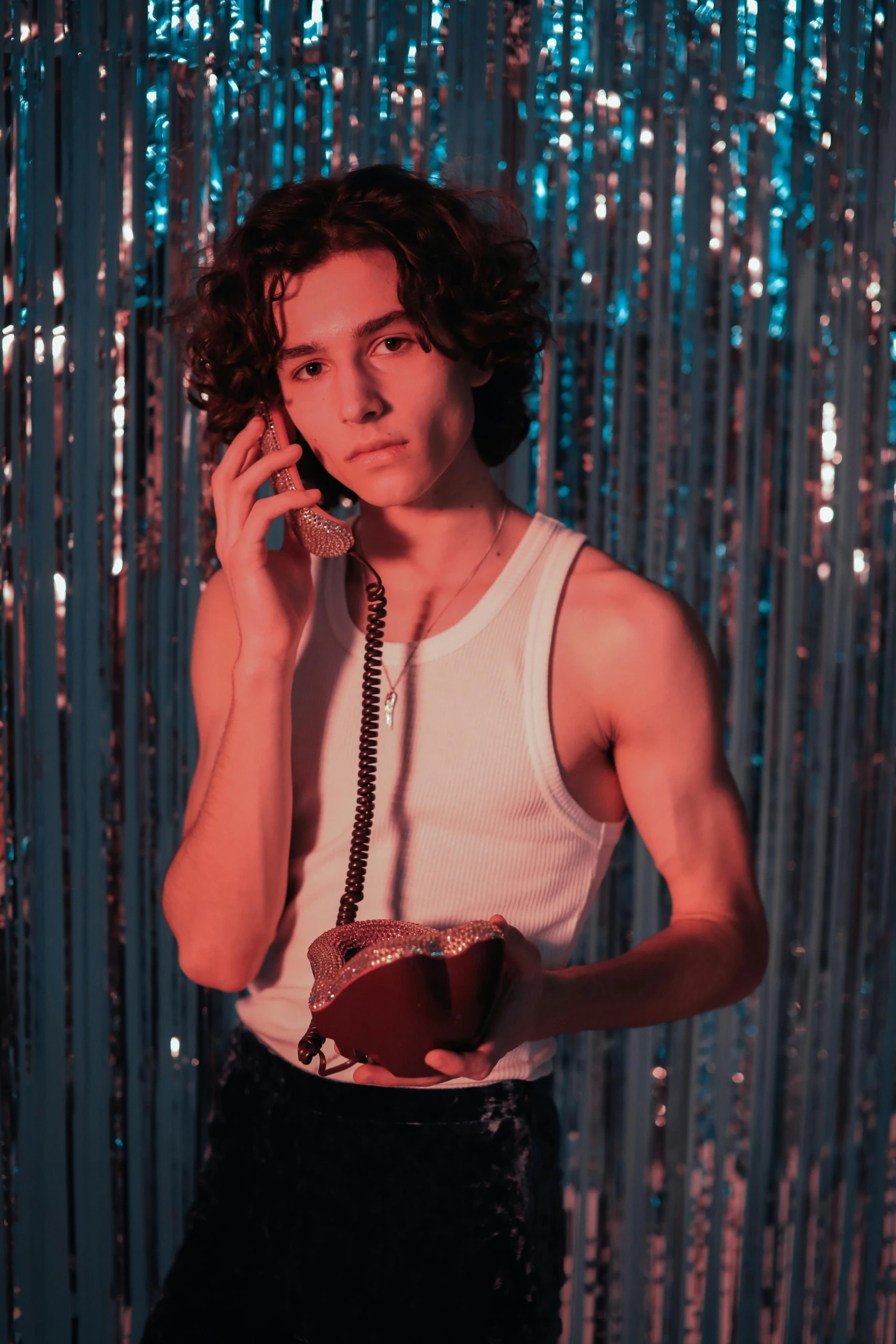 a man standing in front of a wall talking on a cell phone, an album cover, inspired by Nan Goldin, trending on pexels, magic realism, robert sheehan, in a nightclub, nonbinary model, telephone