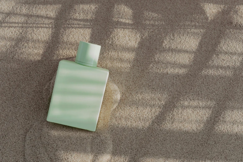 a bottle of perfume sitting on the ground, inspired by Raoul De Keyser, pastel green, carpet, sunbathed skin, eero aarnio