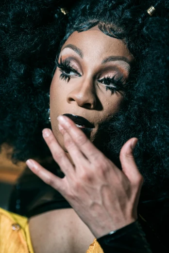 a close up of a person with an afro, trending on pexels, renaissance, ru paul\'s drag race, hand on her chin, under a spotlight, black tendrils