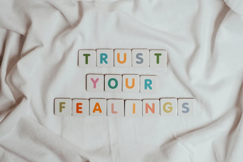 a t - shirt with the words trust your feelings written on it, an album cover, by Robbie Trevino, trending on pexels, healing energy, background image, multicoloured, lying