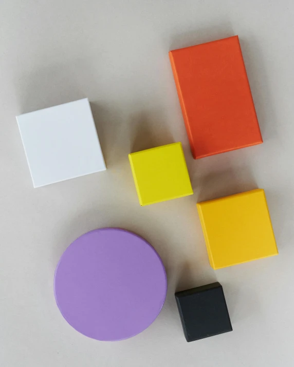 a group of colorful magnets sitting on top of a white surface, inspired by Frederick Hammersley, unsplash, deep purple and orange, solid cube of light, silicone skin, different sizes
