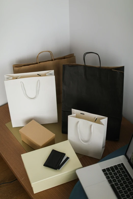 a laptop computer sitting on top of a wooden table, bags on ground, cardstock, thumbnail, mall