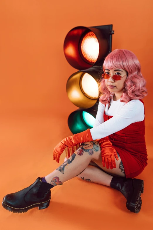 a woman with pink hair sitting in front of a traffic light, light red and orange mood, with a cool pose, velma, red contact lenses