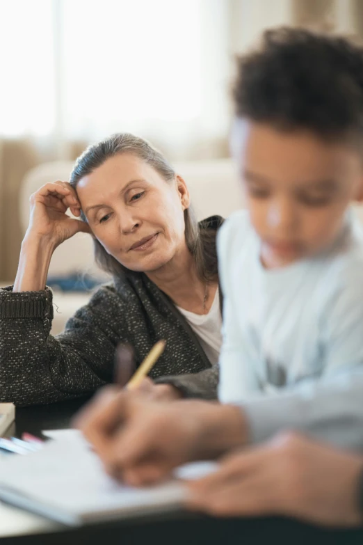 a woman sitting at a table with a child, a child's drawing, looking smart, an elderly, professional grade, over his shoulder