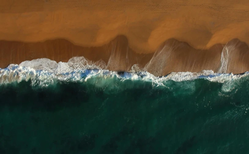 a person riding a surfboard on top of a wave, a minimalist painting, by Eglon van der Neer, pexels contest winner, aerial view of an ancient land, red sand beach, south african coast, sea foam