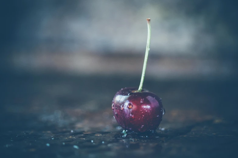 a close up of a cherry on a table, inspired by Elsa Bleda, unsplash, carnal ) wet, background image, ground level shot, a wooden