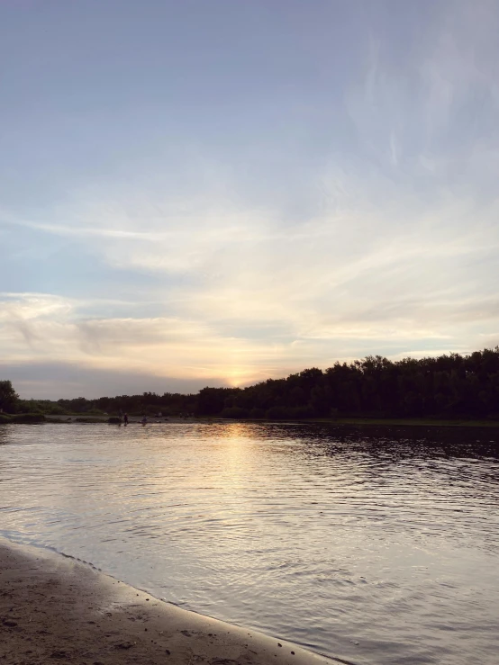 a body of water sitting on top of a sandy beach, the morning river, during a sunset, next to a small river, evening time