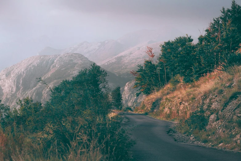 a road with a mountain in the background, by Emma Andijewska, unsplash contest winner, les nabis, in muted colours, late summer evening, slate, threyda