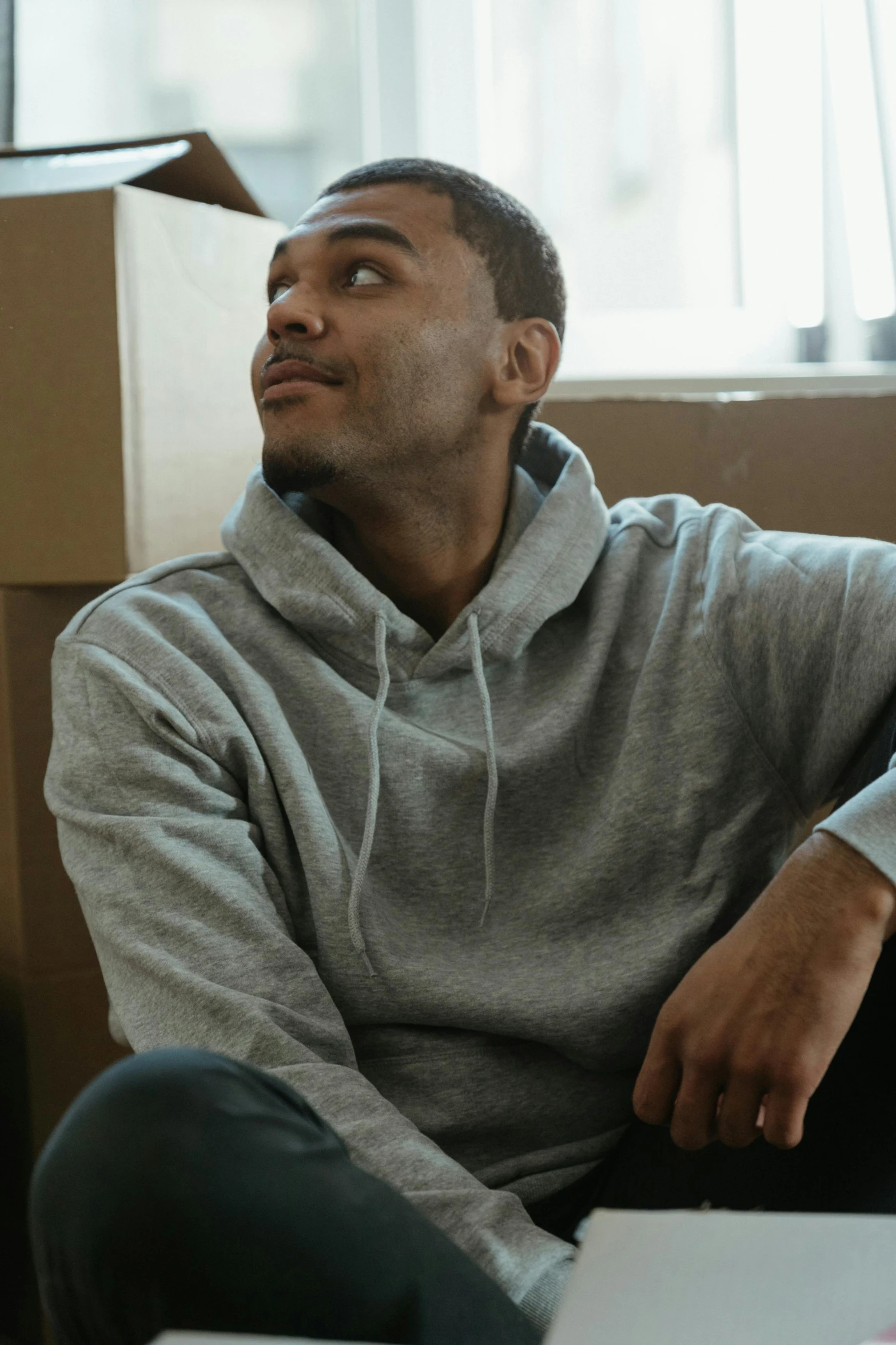 a man sitting on the floor in front of a laptop, inspired by Frank Mason, trending on pexels, renaissance, gray hoodie, slightly smirking, mkbhd, ( ( theatrical ) )