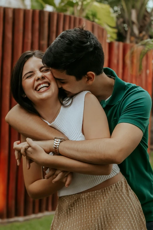 a man and woman hugging each other in front of a fence, pexels contest winner, playful smile, brazil, teen, profile image