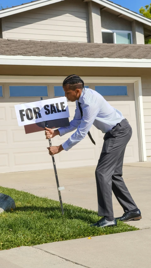 a man holding a for sale sign in front of a house, pexels, realism, holding a thick staff, bending down slightly, 💣 💥💣 💥, vehicle
