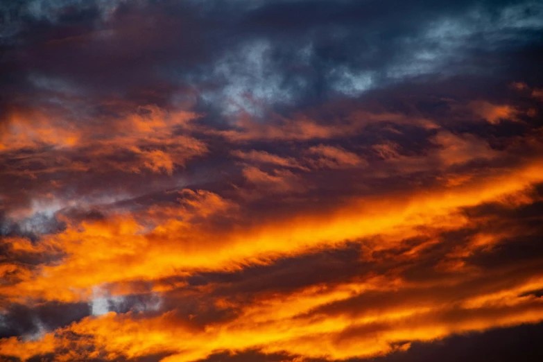 a plane flying through a cloudy sky at sunset, by Lee Loughridge, pexels contest winner, romanticism, fiery palette, orange and blue, ceremonial clouds, a close-up
