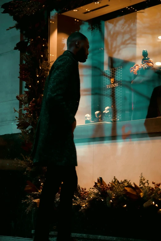 a man that is standing in front of a window, a hologram, by Adam Saks, flower shop scene, holiday season, wearing black overcoat, frank ocean