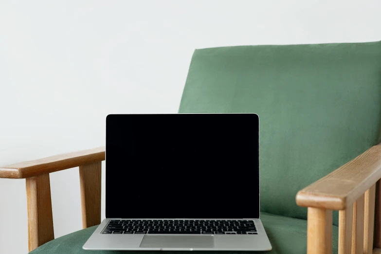 a laptop computer sitting on top of a wooden chair, by Carey Morris, unsplash, computer art, green and black, armchairs, rectangle, using a macbook