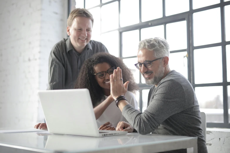 a group of people sitting around a table with a laptop