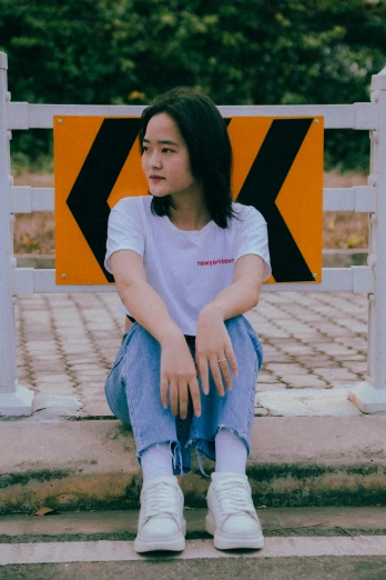 a woman sitting on the side of a road, an album cover, inspired by Cheng Jiasui, pexels contest winner, happening, wearing a t-shirt, serious expression, in front of white back drop, tomboy