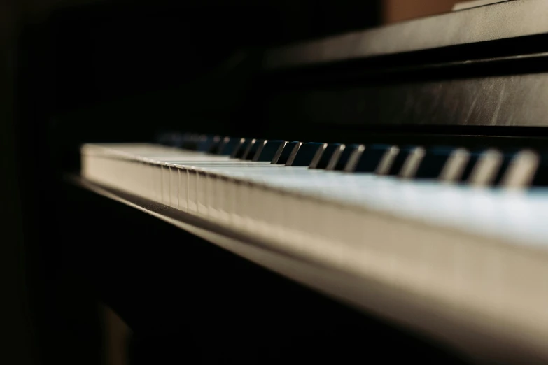 a close up of the keys of a piano, by Niko Henrichon, unsplash, photorealism, soft light from the side, muted lighting, indoor shot, close up shot from the side