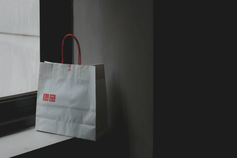 a paper bag sitting on a window sill, by Hiroshi Honda, pexels contest winner, minimalism, red and white neon, gif, presenting wares, facing front