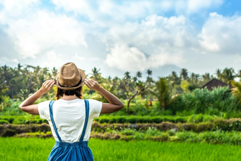 a woman standing in the middle of a rice field, by Julia Pishtar, pexels contest winner, wearing a straw hat and overalls, sri lankan landscape, looking at the sky, avatar image