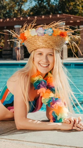 a woman laying on the edge of a swimming pool, by Robbie Trevino, rainbow corals, with straw hat, kristen bell, official photo