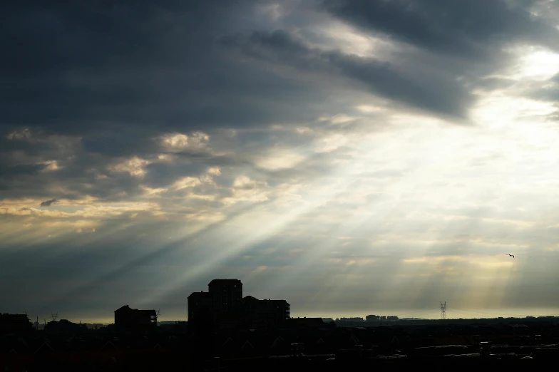 the sun shines through the clouds over a city, a picture, shafts of sunlight in the centre, multiple stories, documentary photo