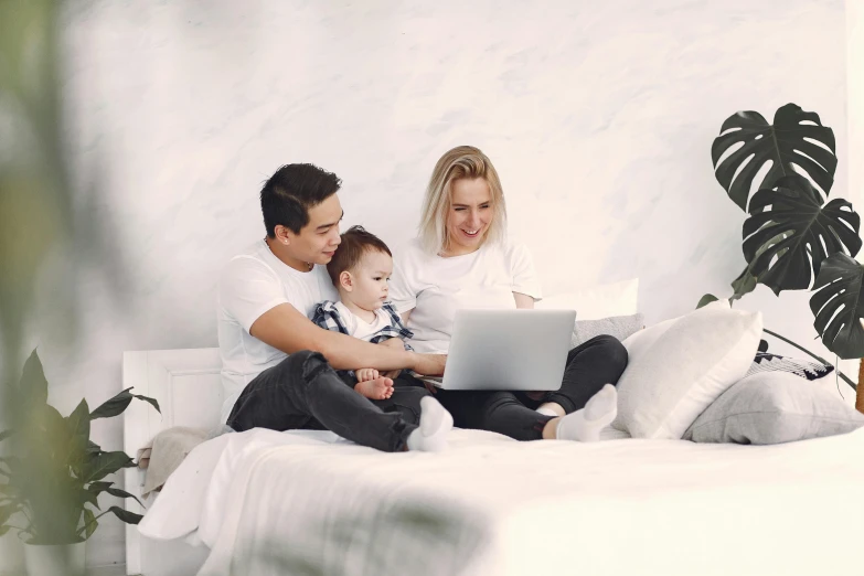 a man and woman sitting on a bed with a baby, pexels, computer art, australian, laptops, white, rectangle