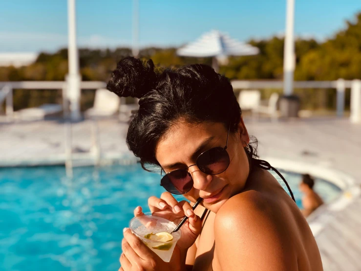 a woman in a bikini drinking a drink by a pool, a portrait, unsplash, morena baccarin, justina blakeney, mia khalifa, sunny day time