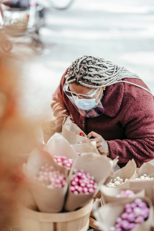 a woman in a face mask looking at flowers, pexels contest winner, process art, candy decorations, packaging, construction, egypt