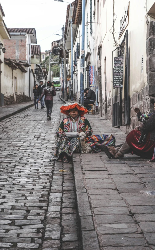 a group of people sitting on the side of a street, inspired by Steve McCurry, pexels contest winner, quito school, cobblestone road, she is dressed in shaman clothes, sleepy, woman with hat