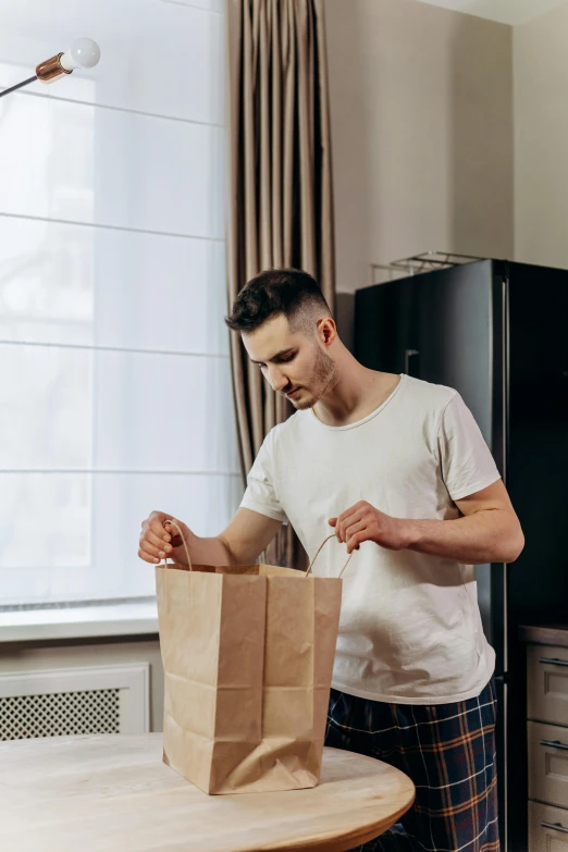 a man standing in a kitchen holding a paper bag, a stock photo, pexels contest winner, leaving a room, handsome man, packaging, 4l