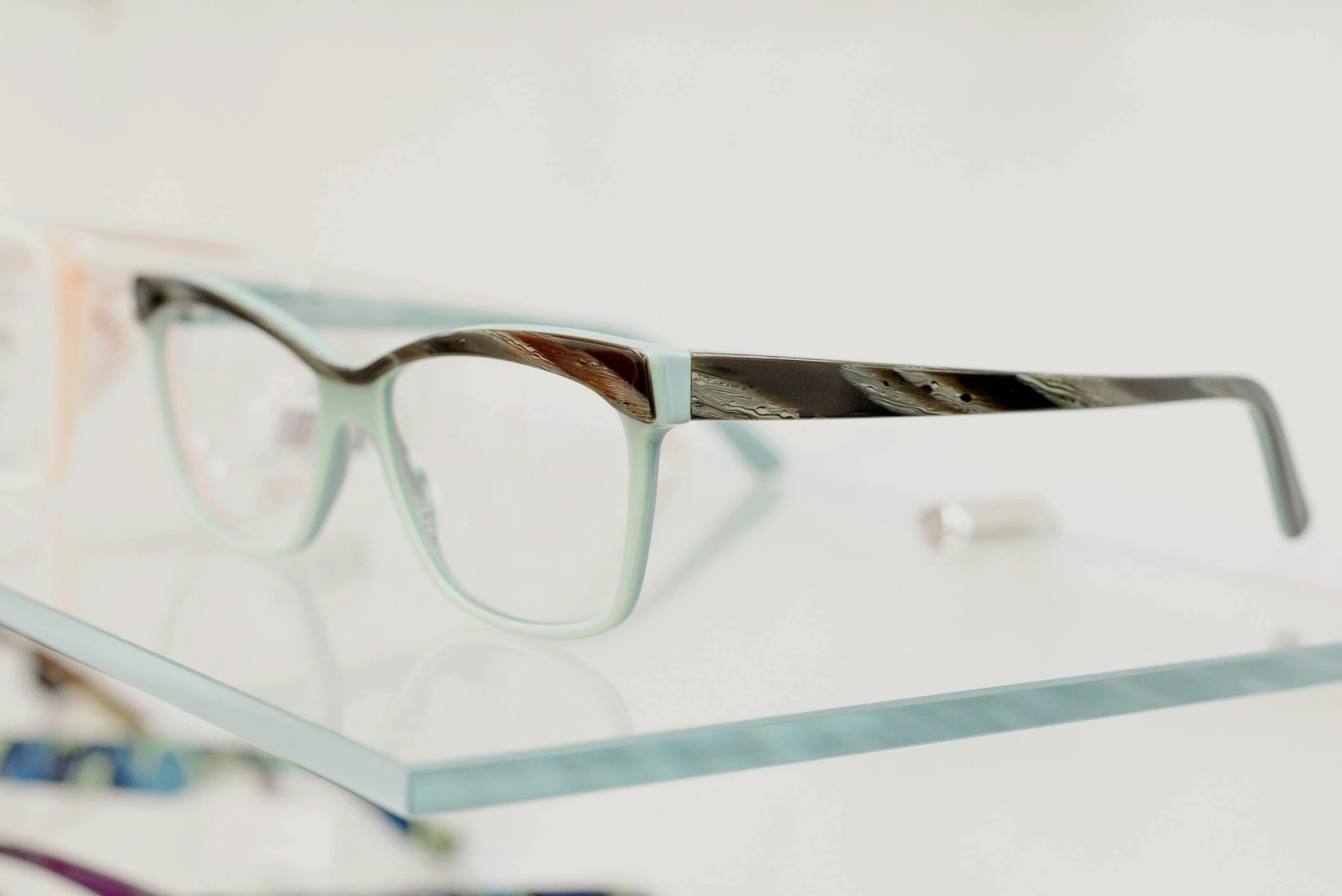 a pair of glasses sitting on top of a glass shelf, white and teal garment, close-up photograph, various posed, framing