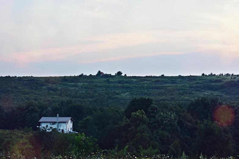 a white house sitting on top of a lush green hillside, an album cover, by Attila Meszlenyi, unsplash contest winner, late summer evening, old american midwest, panorama, cottagecore