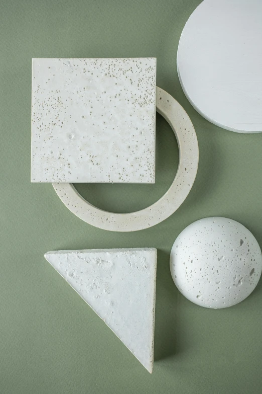 a group of objects sitting on top of a green surface, inspired by Emil Carlsen, concrete art, sleek white, detailed product shot, architectural finishes, varying dots