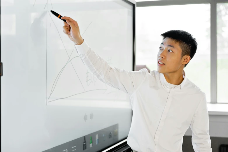 a man standing in front of a whiteboard writing on it, a computer rendering, inspired by Feng Zhu, interactive art, in australia, product introduction photo, close up to the screen, asian male