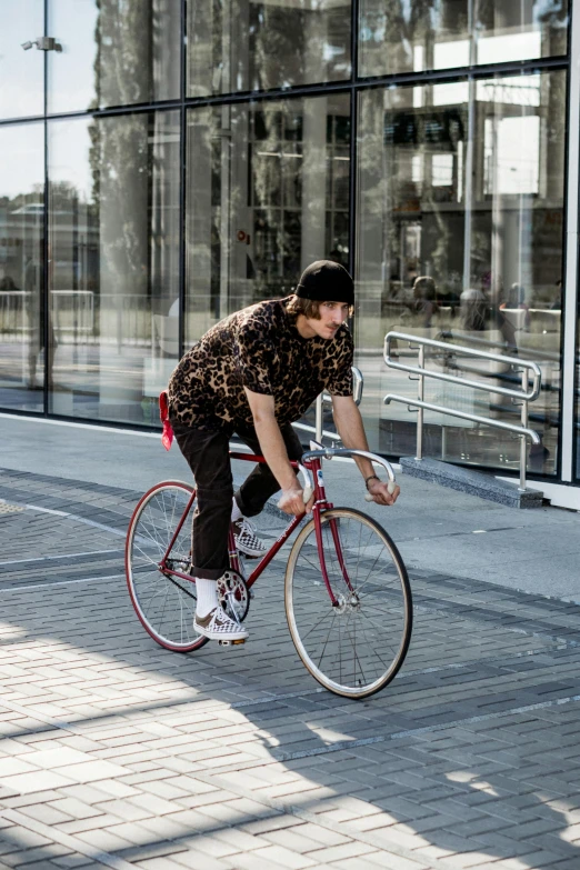 a man riding a bike down a sidewalk next to a building, by Nina Hamnett, pexels contest winner, patterned clothing, maroon, tom of finland style, wearing skate helmet